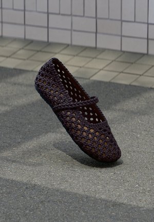 Chaussure plate en tissu tissé violet foncé avec un design perforé, une texture lisse et une semelle plate. Dotée d'une bride décorative sur le cou-de-pied.