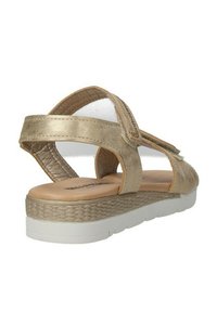 Sandali metallici oro con superficie testurizzata, design aperto, cinturino regolabile e suola intermedia in stile juta intrecciata su una suola in gomma bianca.