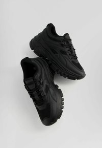 Czarne buty sportowe z połączeniem gładkiego i oddychającego materiału siateczkowego. Gruba gumowa podeszwa z teksturowanym bieżnikiem. Klasyczny wzór sznurowany.
