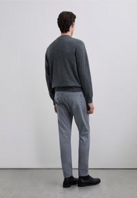 Grå strikket sweater, smalle lysegrå bukser og sorte ankelstøvler. Sweateren har ribbet kant og manchetter. Minimalistisk design med blød tekstur.