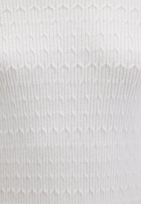 Weißer, strukturierter Stoff mit sich wiederholendem sechseckigem Muster und vertikaler Rippung. Weiche Textur mit glattem Finish.