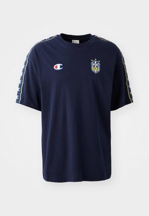 Marineblå T-shirt med korte ærmer lavet af bomuld, med Champion-logo, et fodboldklubemblem og mønstrede detaljer langs ærmerne.