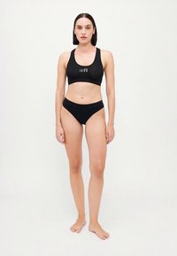 Schwarzer Sport-BH und passender hochgeschnittener Bikini mit minimalistischem Design und Logo auf der Vorderseite. Glattes, elastisches Material.