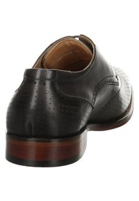 Schwarzer Lederschuh mit durchbrochenem Muster, runder Ferse und glatter Textur. Braune Holzsohle mit subtilen Akzentlinien.