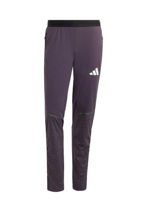 Lila Sporthose mit schwarzem Bund, seitlichen Reißverschlusstaschen, reflektierendem Adidas-Logo am rechten Oberschenkel und gemusterten unteren Hosenbeinen.