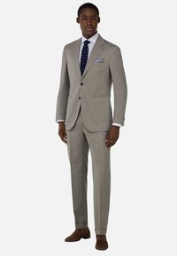 Traje de color gris claro hecho de tejido texturizado, con dos bolsillos, diseño de un solo pecho y una corbata de lunares azules con un pañuelo a juego.
