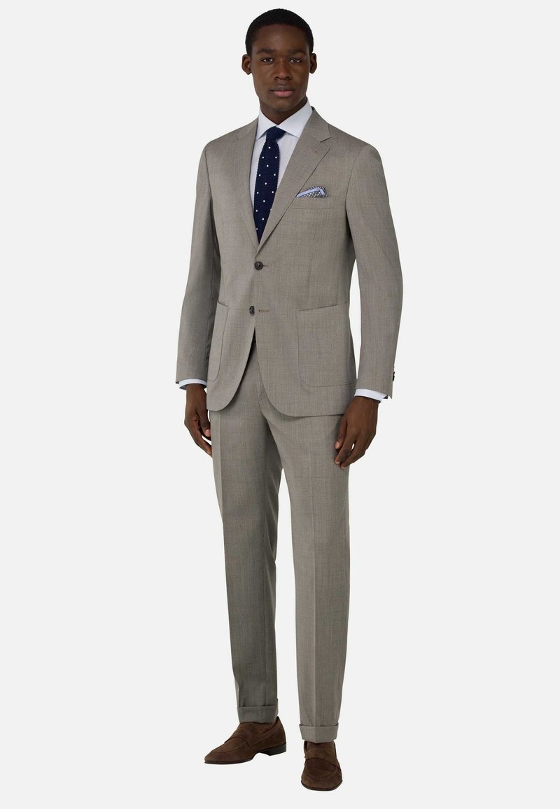 Traje de color gris claro hecho de tejido texturizado, con dos bolsillos, diseño de un solo pecho y una corbata de lunares azules con un pañuelo a juego.