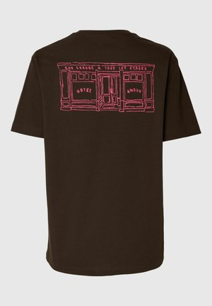 Tumepruun t-särk roosa joonistusega poesildi kujutisega, millel on kiri „Hotel Amour“ ja akende kohal prantsuskeelne tekst.