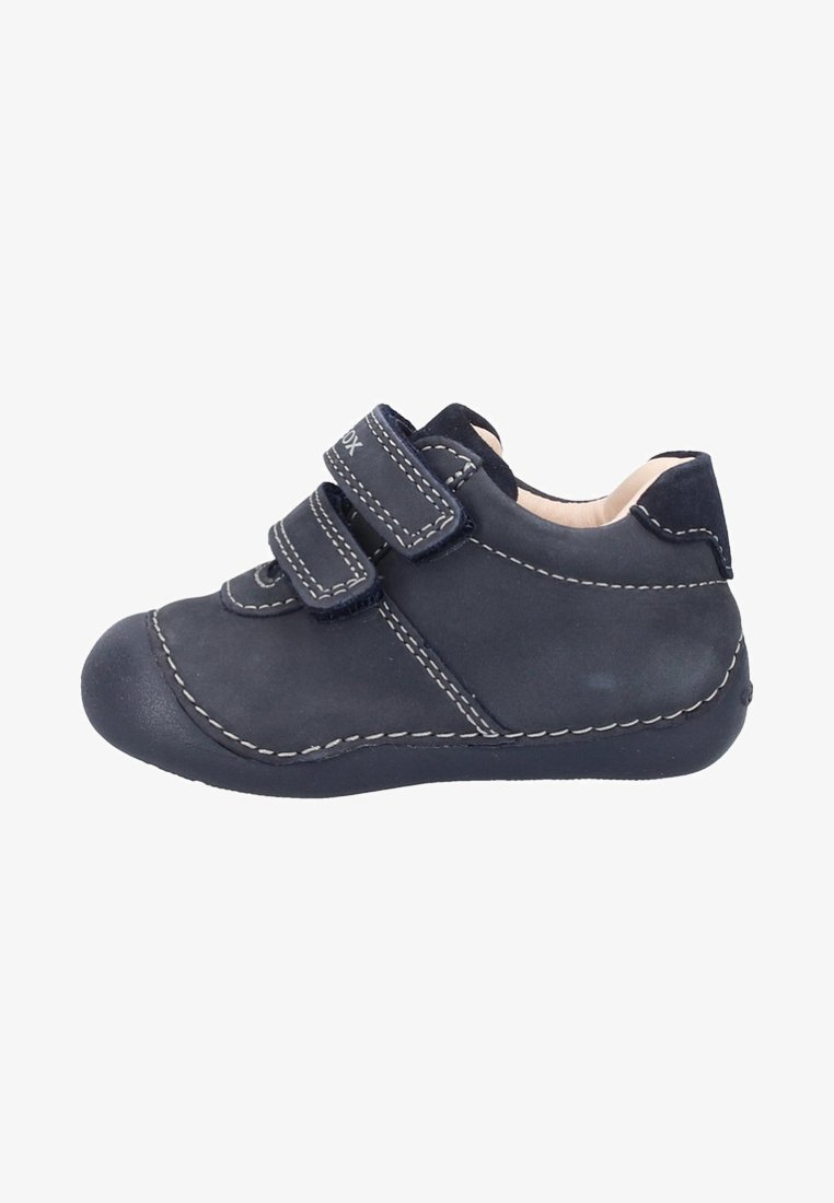 Scarpa per bambino blu navy realizzata in morbido camoscio, con due cinturini in velcro, impunture bianche, punta rotonda e suola in gomma texturizzata.