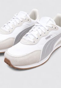 Zapatillas deportivas blancas y grises con materiales de ante y textil, que cuentan con un cuello acolchado, cierre con cordones y suela de goma.