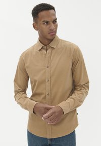 Bežinė medvilninė marškiniai ilgomis rankovėmis, su subtilia tekstūra, su apykakle, priekyje mygtukais ir pritaikytu siluetu.