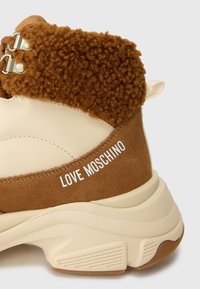 Chunky bež i smeđi tenisice s teksturiranim tkaninom oko gležnja i "LOVE MOSCHINO" natpisom na nubuk peti.