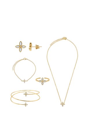 Ensemble de bijoux en or avec des accents de pierres claires en forme de fleur, comprenant des boucles d'oreilles, un collier, une bague, un bracelet et un jonc sur fond blanc.