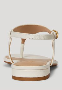 Białe sandały z teksturowanym paskiem, płaską podeszwą i złotym akcentem z klamrą. Gładka wyściółka wewnętrzna dopełnia całość projektu.