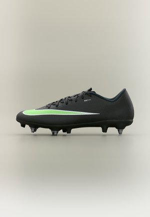 Botas de fútbol negras Nike con swoosh verde y blanco, cordones negros y tacos metálicos en la suela.