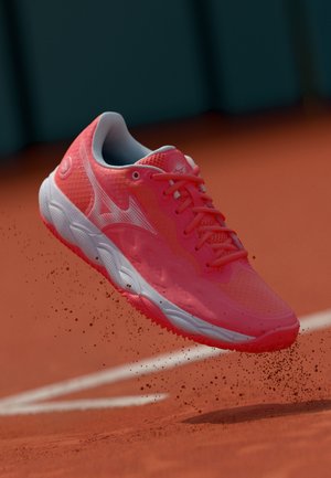Scarpe da ginnastica rosa con tomaia in rete e corpo testurizzato. Presenta suola bianca con motivi di trazione, lacci e dettaglio del logo sul lato.