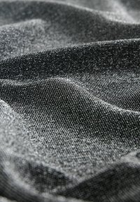 Tissu gris avec une surface texturée, présentant des fils métalliques subtils, créant une apparence ondulée. Le gros plan met en valeur le détail fin et la profondeur du matériau.