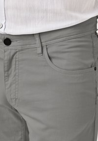 Gray cotton pants with a smooth texture, featuring a belt loop, button closure, and a front pocket. Subtle stitching detail along the edges.