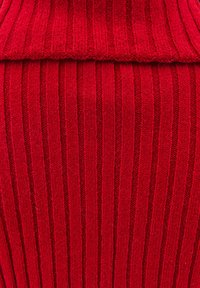 Czerwona dziana tkanina z pionowym prążkowanym wzorem, z złożonym dekoltem na górze. Materiał wydaje się miękki i gruby.