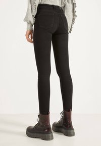 Svarta slim fit jeans med hög midja och två bakfickor, kombinerat med svarta snörda militärstövlar med tjock sula.