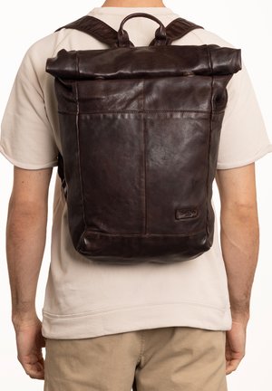 Brown leather roll-top backpack with textured finish, single strap, and side pocket; features adjustable straps and a loop handle.