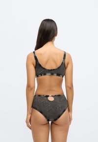 Σετ μαγιό δύο τεμαχίων με σκούρο σχέδιο tie-dye. Το τοπ διαθέτει φαρδιές τιράντες και χαμηλή πλάτη, ενώ το κάτω μέρος με ψηλή μέση έχει κυκλικό άνοιγμα.