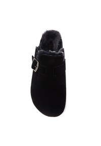 Black suede slipper with a soft fur lining, featuring an adjustable strap with a silver buckle. Round toe and flat sole.