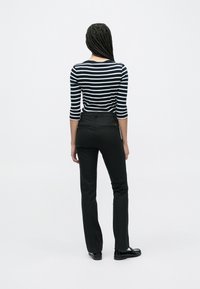 Pantalon noir évasé associé à un haut rayé bleu marine et blanc, doté de manches trois-quarts et d'une silhouette ajustée.
