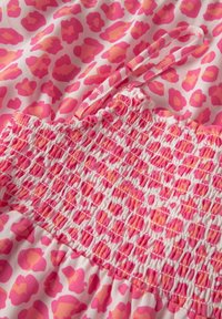 Rosa und orange Leopardenmusterstoff mit smockiertem Nähten und einem schmalen Trägerdetail auf einem leichten Kleidungsstück.