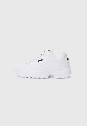 Baskets basses blanches FILA avec semelle épaisse, logo sur le côté et le talon, et fermeture à lacets sur un fond clair.