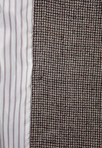 Tkanina z białym materiałem z wąskimi brązowymi paskami po lewej stronie oraz teksturowanym brązowym wzorem w kratę houndstooth po prawej stronie.