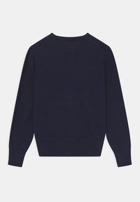 Tummansininen neulepusero, jossa on pitkät hihat, röyhelökaulus ja -hihansuut, sekä sileä pinta ja klassinen istuvuus. Takakuvasta näkyy.