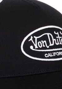 Casquette de baseball noire avec un logo ovale brodé en blanc comportant le texte "Von Dutch" et "CALIFORNIA". Le tissu est texturé, avec une visière courbée.