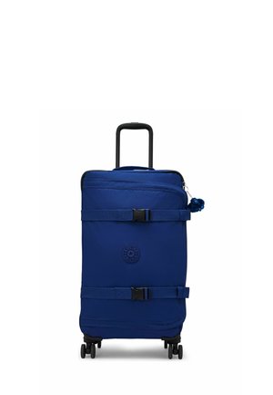 Valise bleue souple à roulettes avec deux sangles réglables, une poignée télescopique et un petit porte-clés en peluche sur la fermeture éclair du dessus.