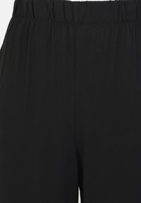 Pantaloni a gamba larga neri con cintura elastica. Il materiale sembra morbido e leggero con una texture liscia. Nessun motivo o accento visibile.