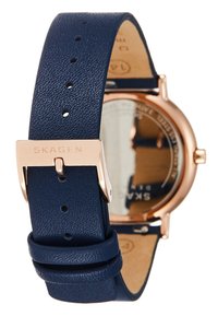 Niebieski skórzany pasek do zegarka o teksturowanym wykończeniu, z różowozłotą metalową klamrą, regulowany za pomocą otworów, połączony z okrągłą tarczą zegarka.