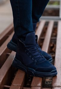 Bottes chevilles bleu marine en combinaison de suède et de tissu, dotées de lacets solides, d'un col rembourré et d'une semelle en caoutchouc texturée.