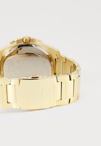 Ceas de mână din aur cu brățară din linkuri metalice, carcasă rotundă, bezel lucios și spate neted și reflectorizant.