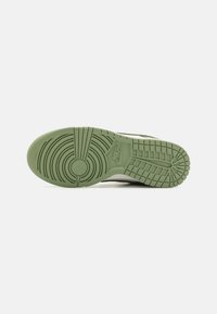Nike könnyű cipők, amelyeken textúrázott zöld gumitalp található, körkörös mintákkal és egy kiemelkedő logóval, alulról nézve.