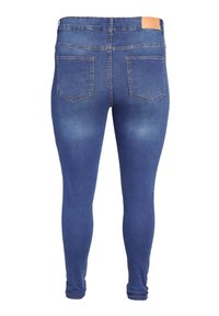 Modre ozke kavbojke iz jeansa z dvema zadnjima žepoma in rjavim usnjenim označevalnim členkom na pasu, prikazane od zadaj.