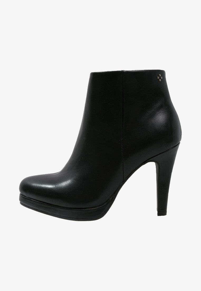 Bottine en cuir noir avec un talon haut de 9 cm, bout arrondi et petite décoration en clous métalliques près du col.