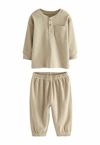 Conjunto de dos piezas de punto acanalado en color beige, que incluye una camiseta henley de manga larga con un bolsillo y pantalones de cintura elástica con puños ajustados.