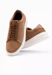 Baskets en suede marron avec des semelles en caoutchouc blanc. Les caractéristiques incluent un bout rond, un laçage à l'avant et un accent en cuir beige au niveau du talon.