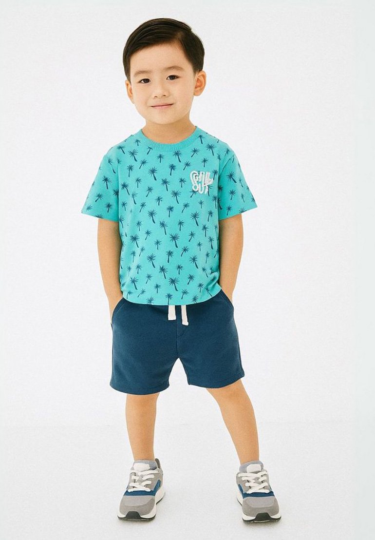Camiseta turquesa con patrón de palmeras, detalle de logo, combinada con pantalones cortos marino y zapatillas grises con acentos azules. Conjunto casual de verano.