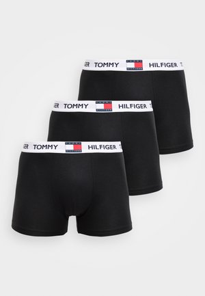 Mustad puuvillased bokserid, millel on lai valge vööümbermõõt „TOMMY HILFIGER" logoga ja värvimustriga. Kolm paari on üksteise peale virnastatud.