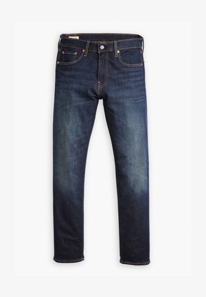 Jeans slim-fit blu scuro con cinque tasche, rivetti in rame e chiusura a bottone, esposti piatti su uno sfondo bianco.