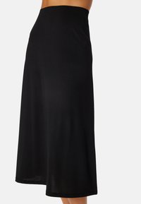 Zwarte culotte rok van een gladde, rekbare stof. Heeft een hoge tailleband en wijde pijpen, wat zorgt voor een vloeiende silhouet.