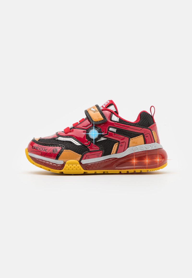 Rote Sneaker mit schwarzem Mesh und orangefarbenen Akzenten, ausgestattet mit einem Klettverschluss, einem auffälligen geometrischen Design und einer durchsichtigen gelben Sohle.