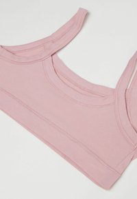 Světlá růžová braletka z měkké, elastické tkaniny. Má široké ramínka a hladký, zaoblený výstřih. Bezešvý design bez vzorů.