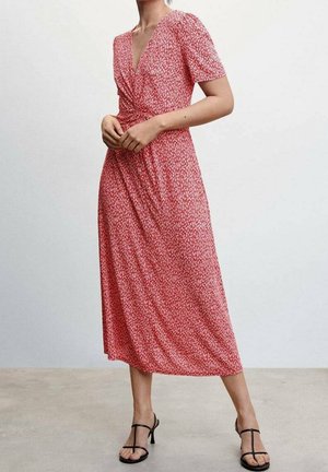 Robe portefeuille à fleurs rouges avec des manches courtes, un col en V et un détail de taille nouée. Tissu doux avec une jupe fluide et une coupe longueur cheville. Sandales noires.